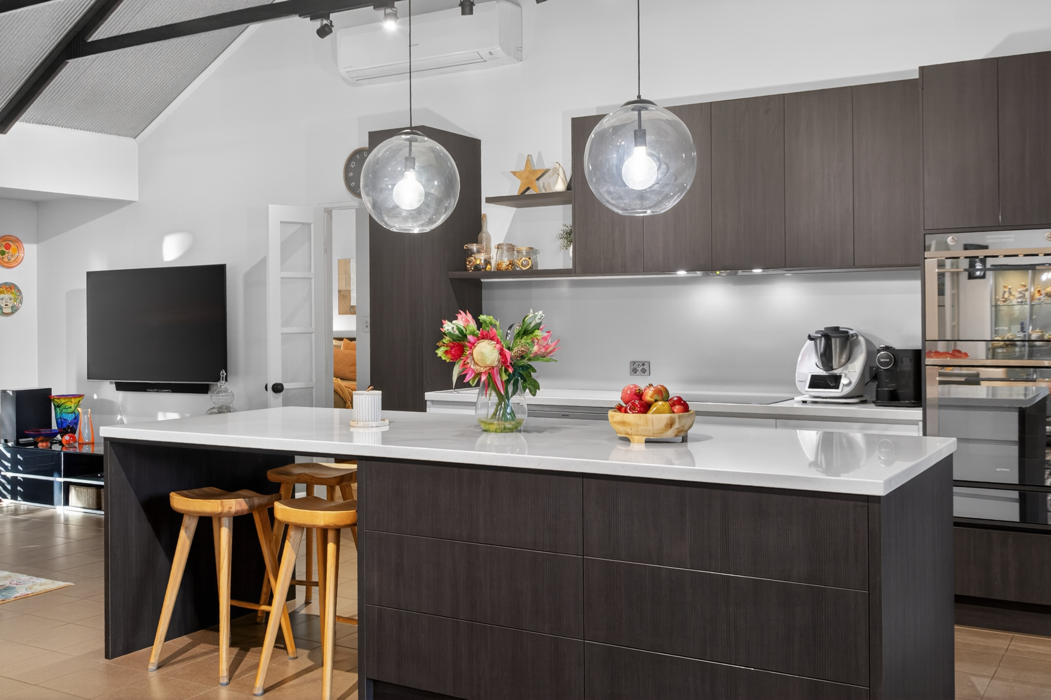 Adelaide stone kitchen benchtop with natural veining and brass tap on walnut cabinetry in soft daylight